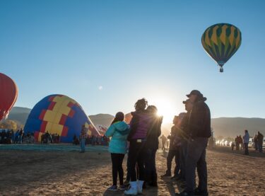A crowd admires the hot air balloons as they prepare to lift off