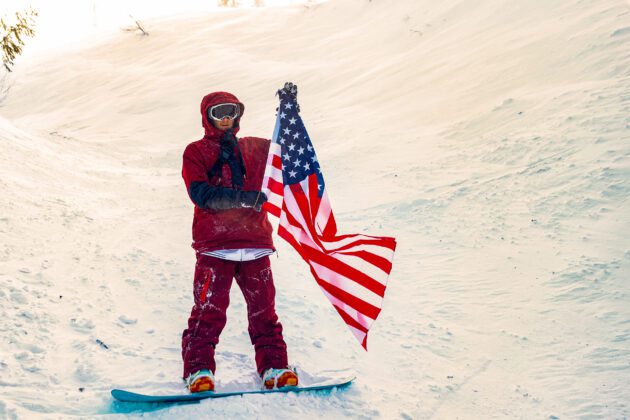 A snowboarder holding an American flag