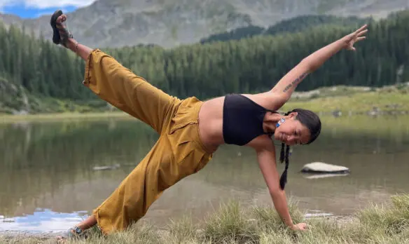 Woman doing yoga near a lake in the mountains