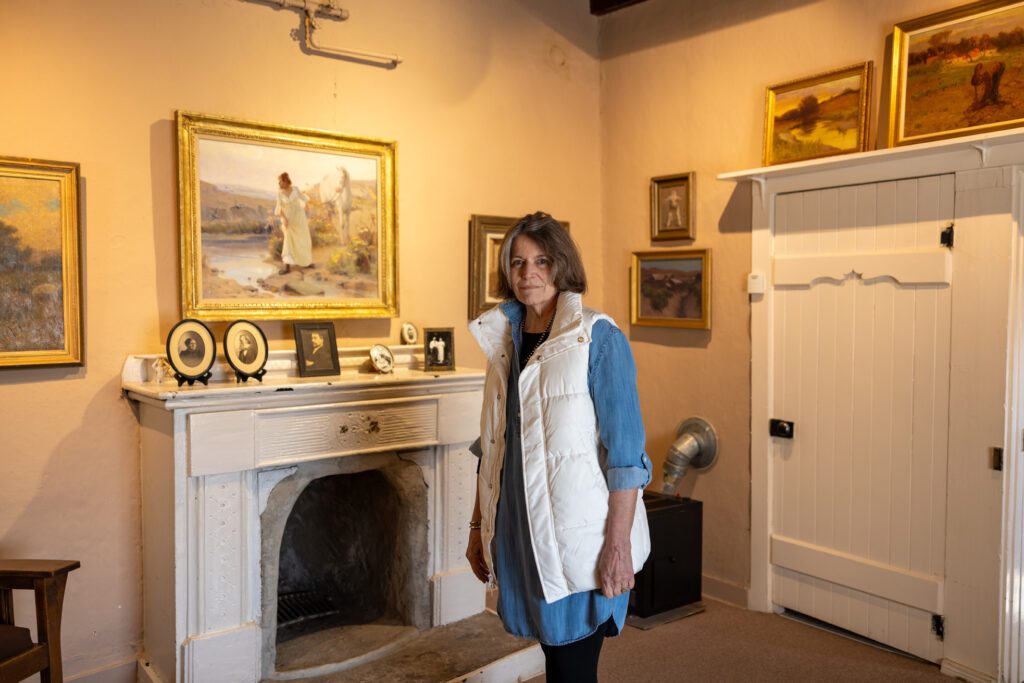 A woman stands in the middle of a living room in front of a fireplace